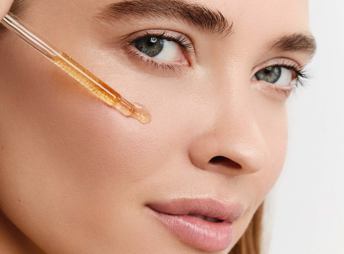 Gros plan sur un visage avec application d’un sérum à l’aide d’une pipette.