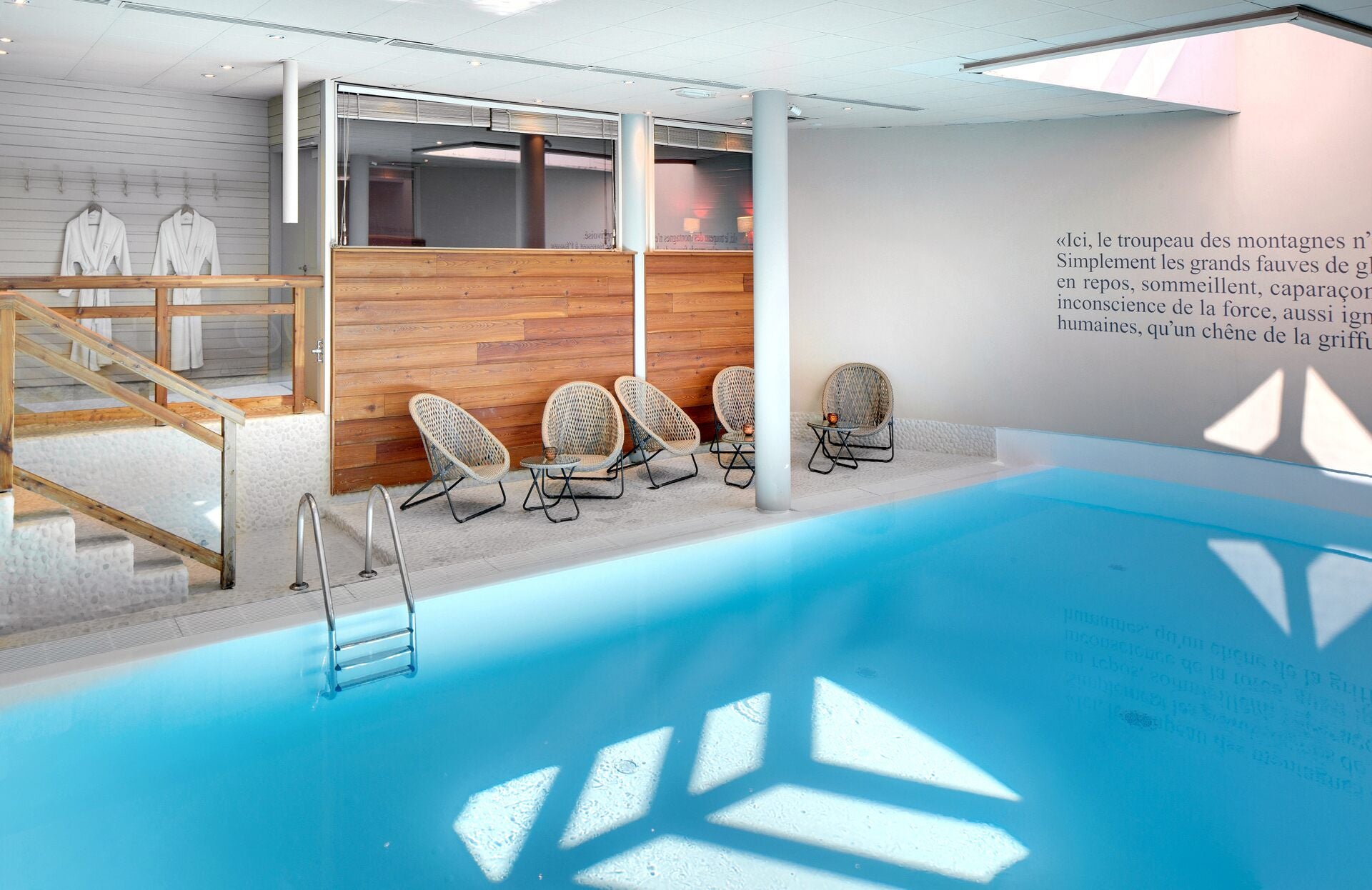Un espace bien‑être lumineux et contemporain, où une piscine intérieure aux eaux apaisantes est sublimée par une architecture épurée et des matériaux chaleureux. Entre bois, lumière naturelle et assises élégantes, ce lieu invite à une parenthèse de détente dans une atmosphère calme et raffinée.