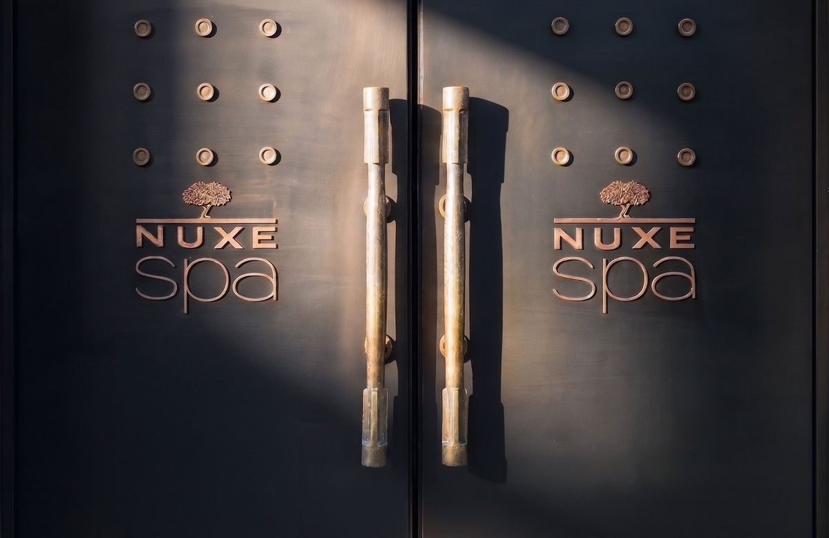 Entrée du Spa NUXE de l'Hôtel Square : portes sombres ornées du logo NUXE Spa en cuivre et de grandes poignées en laiton