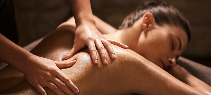 femme allongée se faisant masser le dos par des mains délicates dans une ambiance tamisée