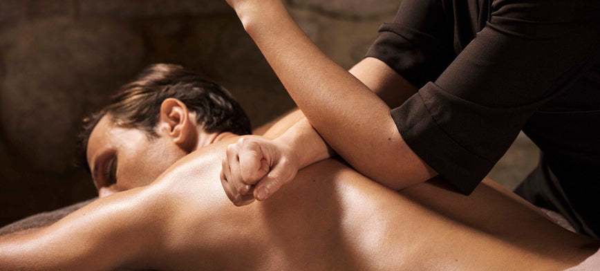 homme allongé en train de se faire masser le dos en profondeur par une personne qui utilise son coude.