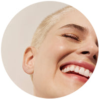 visage de femme sur fond beige qui éclate de rire 