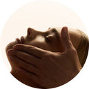 Visage allongé recevant un massage du visage.