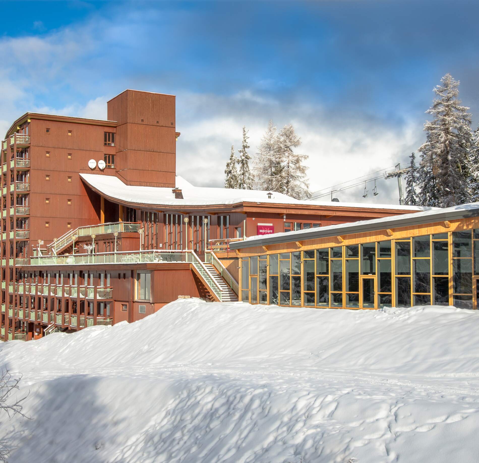Façade élégante du spa Altezza aux Arcs, baignée de lumière, nichée dans un paysage enneigé. 