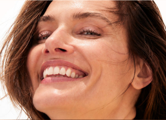 Portrait en gros plan d’un visage souriant avec les cheveux balayés par le vent