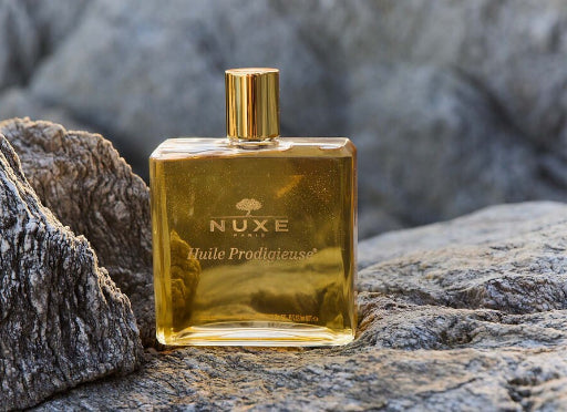 Flacon d’Huile Prodigieuse NUXE mis en scène sur des rochers