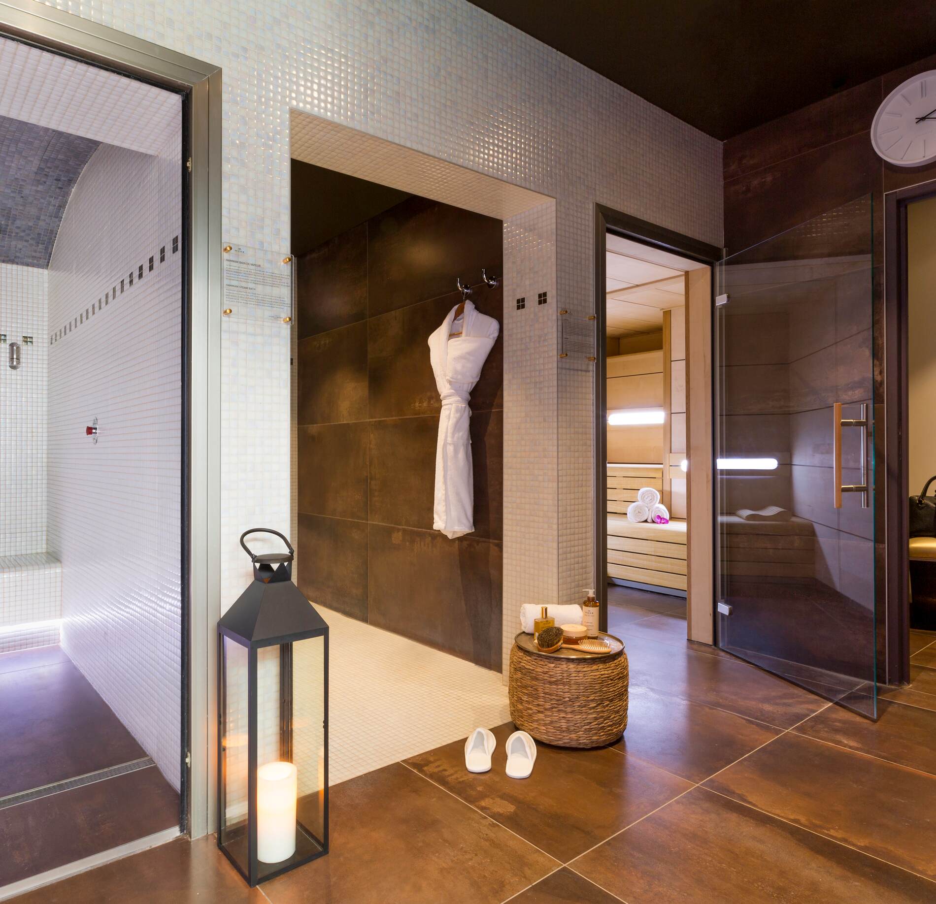 Espace bien-être élégant du spa NUXE à l’Hôtel de la Poste Troyes, avec douche contemporaine, peignoir suspendu, lanternes décoratives et accès à un sauna, dans une atmosphère chaleureuse, raffinée et apaisante.