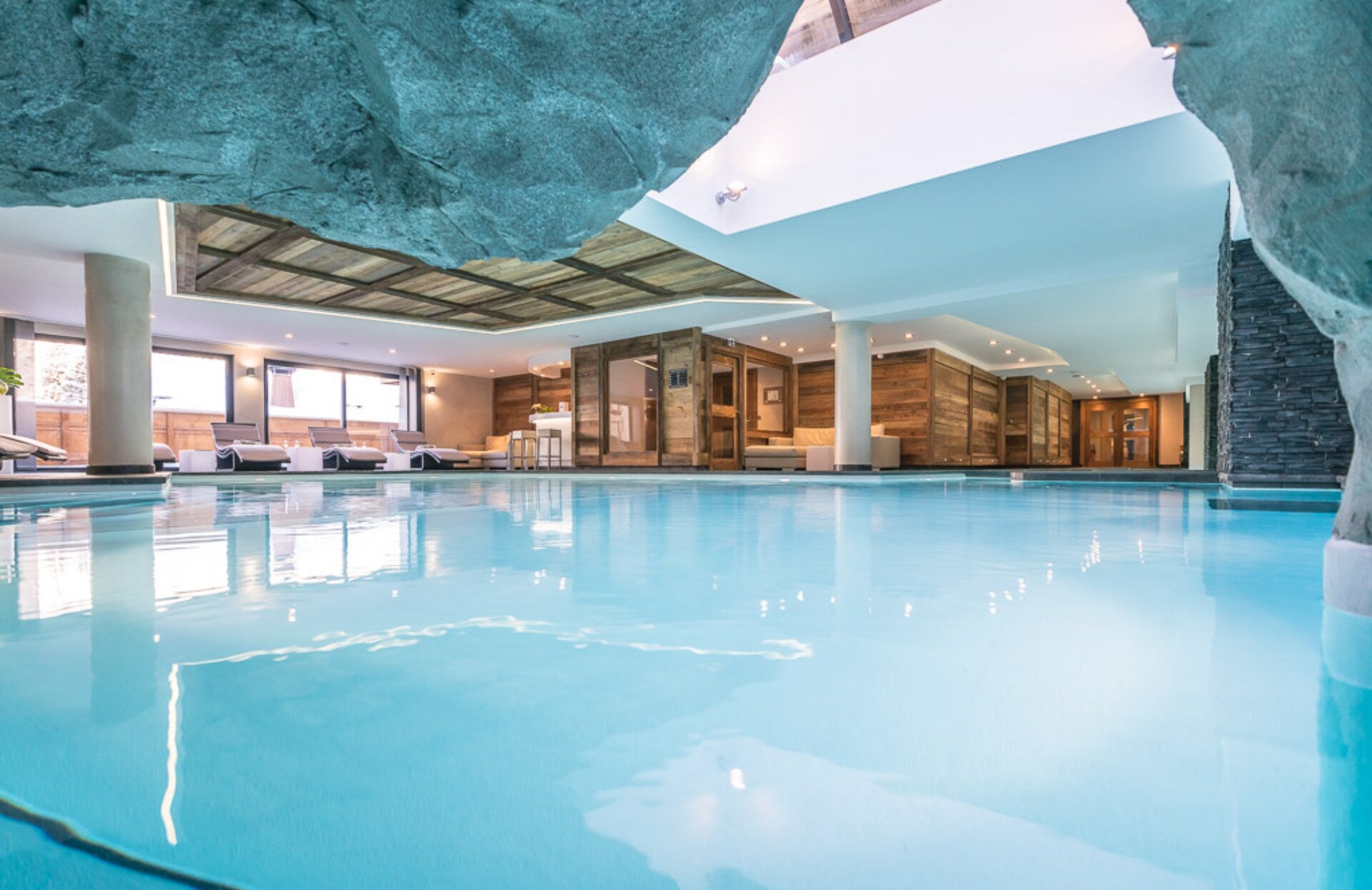 Une vaste piscine intérieure aux eaux cristallines, nichée au cœur d’un espace spa élégant mêlant bois, pierre et touches contemporaines. Baigné de lumière naturelle, ce lieu offre une ambiance apaisante et raffinée, idéale pour une expérience de détente absolue.