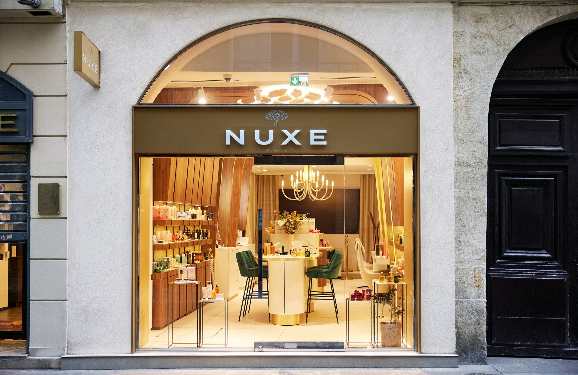 façade de la boutique / spa NUXE situé au 32-34 de la rue Montorgueil. On y voit la vitrine de la rue avec l'enseigne "NUXE", aisi qu'en transparence, l'intérieur de la boutique, des produits, une grande table haute et des chaise hautes autour. 