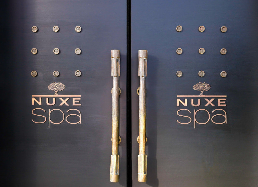 Entrée du NUXE Spa avec portes élégantes ornées du logo de la marque, invitant à une expérience de bien-être et de relaxation dans un cadre haut de gamme.