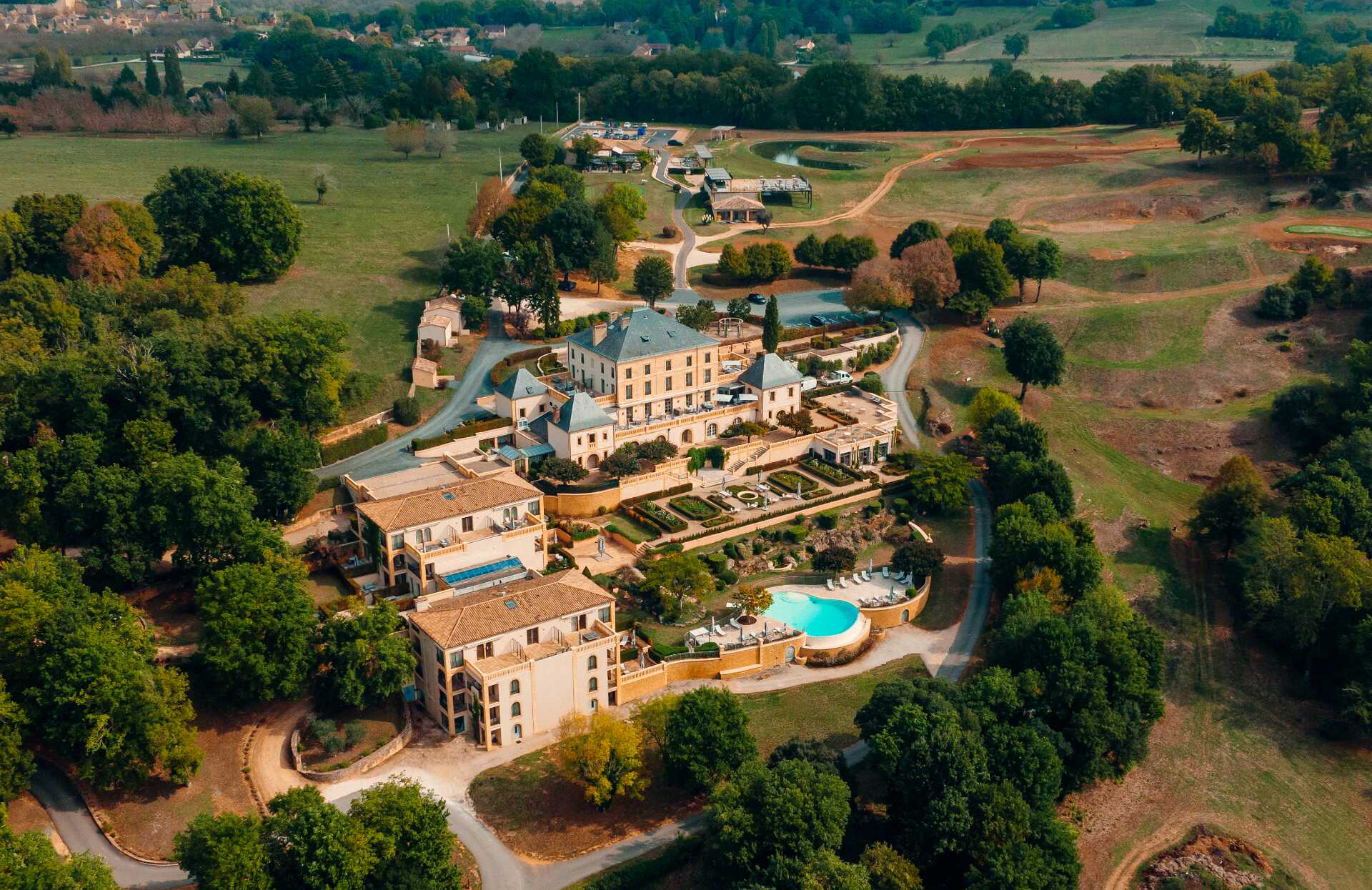Une vue aérienne impressionnante dévoile un vaste domaine entouré de collines verdoyantes, avec une demeure élégante au centre et des jardins parfaitement structurés.
La piscine aux courbes harmonieuses, les allées sinueuses et l’environnement naturel offrent une expérience exclusive, mêlant raffinement, calme et immersion totale.