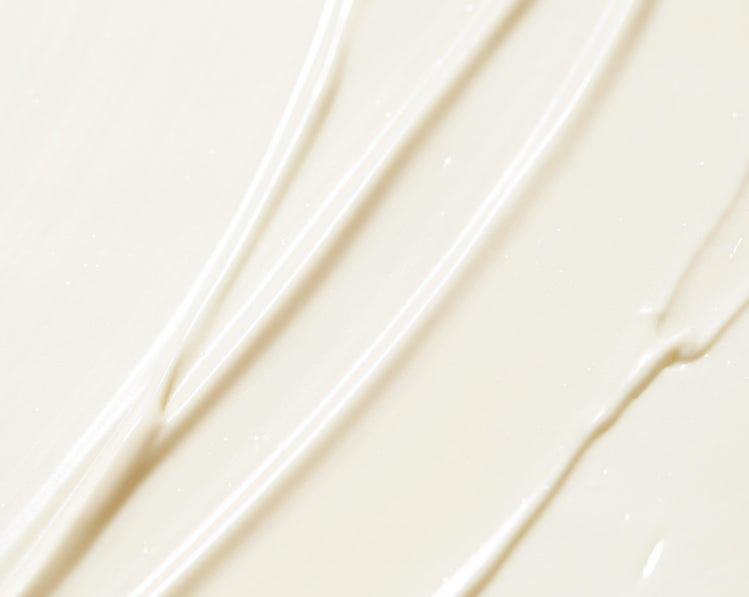 Une surface uniforme de crème blanche est étalée en larges traits lisses. Des sillons parallèles visibles montrent le passage d’un doigt ou d’un outil, créant des lignes douces et régulières.
La texture paraît épaisse et soyeuse, avec des reflets subtils qui captent la lumière. L’ensemble est minimaliste, sans arrière-plan distinct, mettant uniquement en valeur la matière.