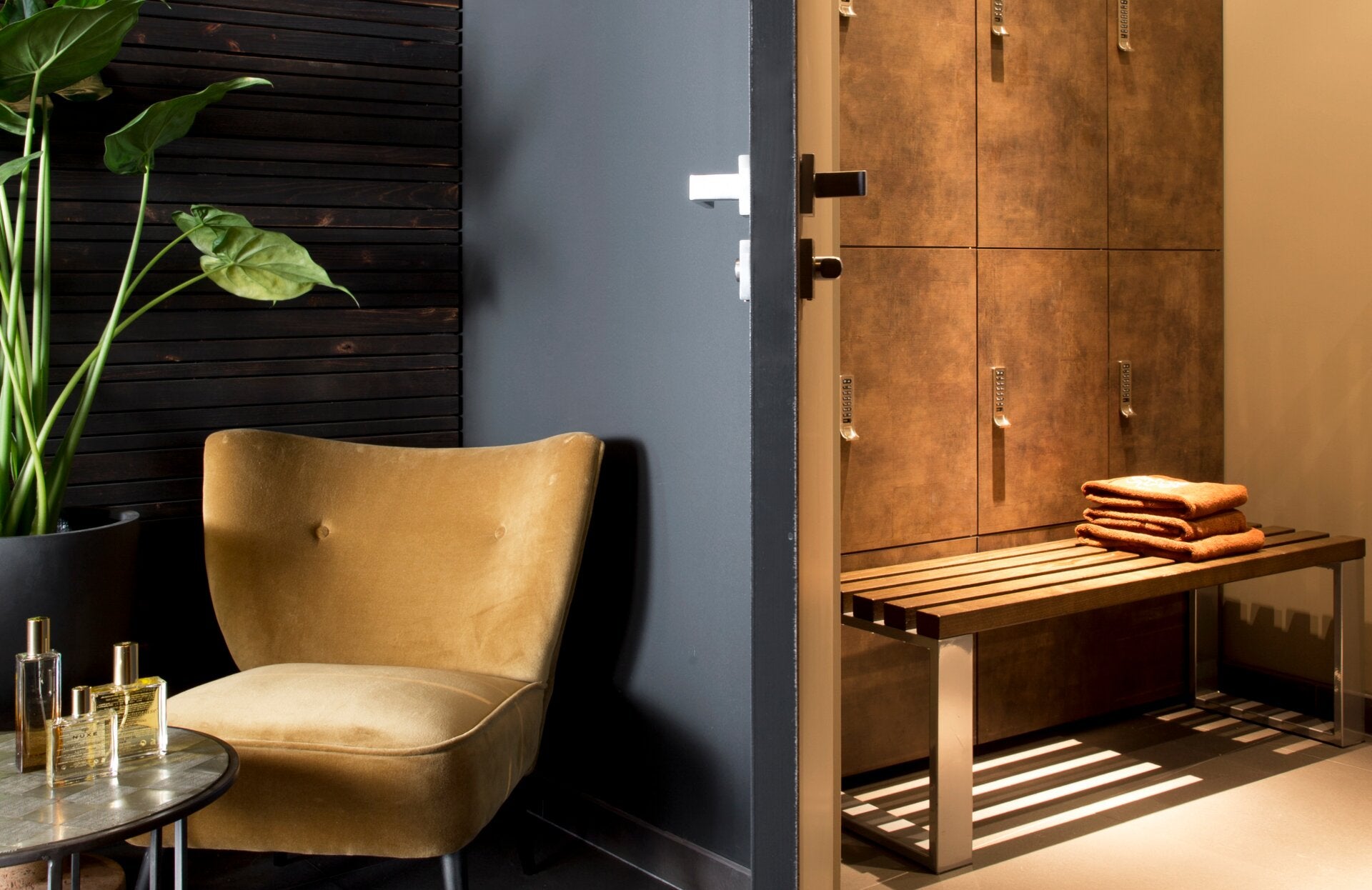 Un espace vestiaire élégant et chaleureux, où les matières nobles comme le bois et le cuir se mêlent à une lumière douce et apaisante. Entre fauteuil confortable, casiers soigneusement alignés et linge délicatement disposé, cet environnement invite à prolonger l’expérience bien-être dans un cadre intimiste et raffiné.