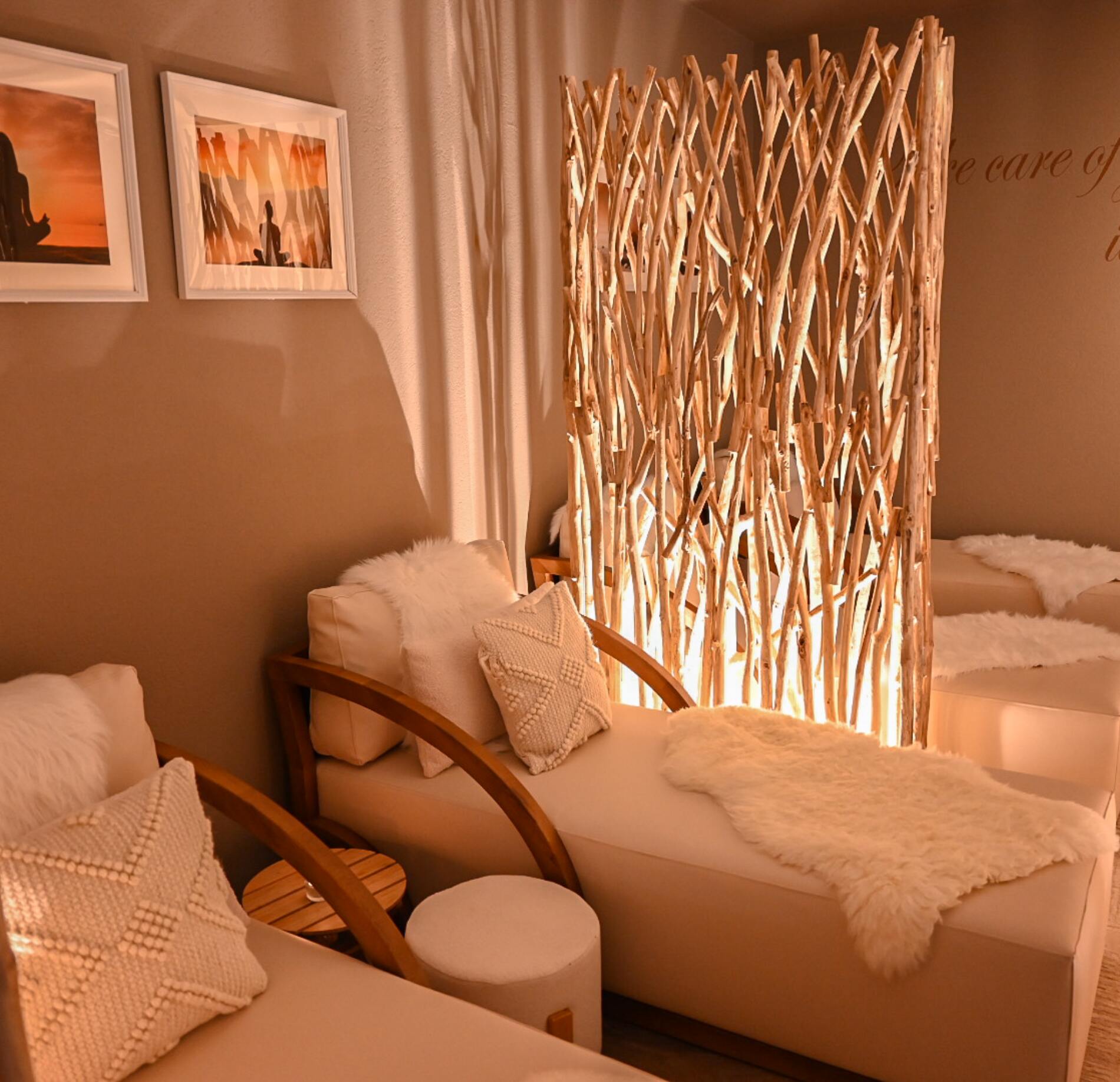 Espace de relaxation intimiste et élégant du spa NUXE, avec fauteuils confortables habillés de textiles doux, éclairage chaleureux et cloison décorative en bois tressé, créant une atmosphère apaisante et cocooning.