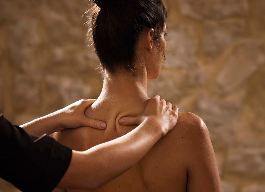 Massage du haut du dos et de la nuque réalisé dans un spa, mettant en avant un moment de détente, de bien-être et de relaxation musculaire.