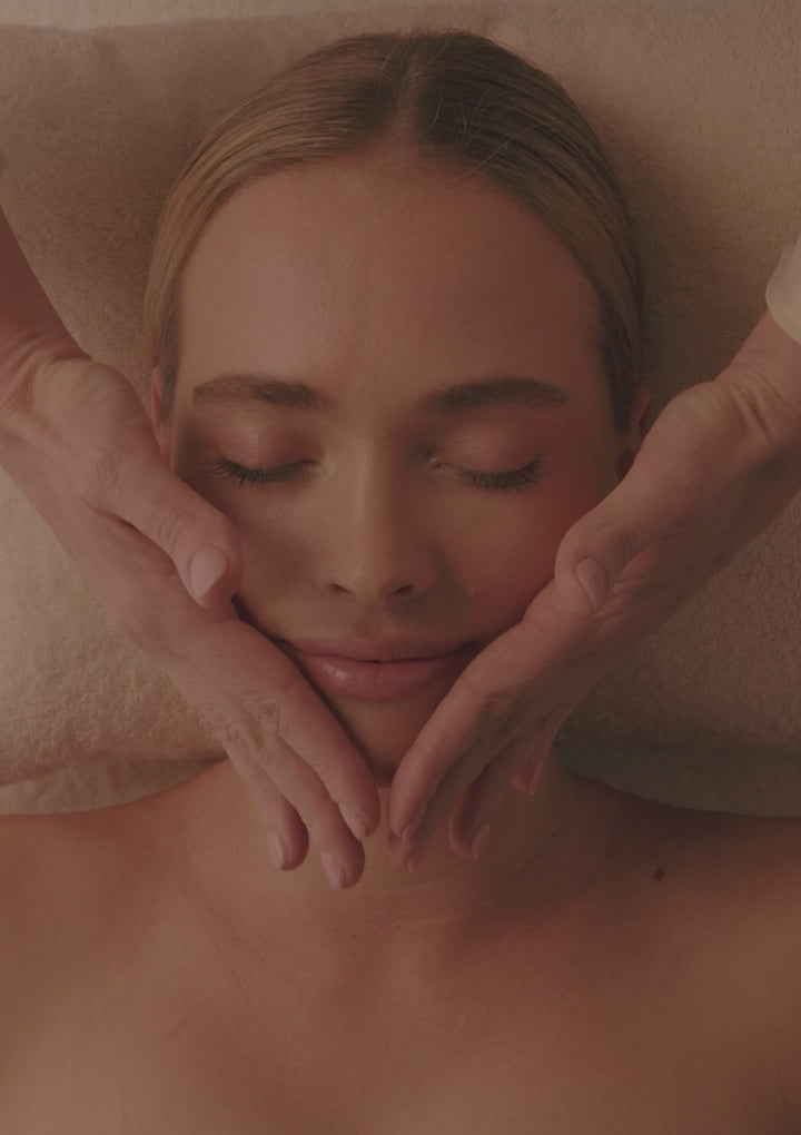 Vidéo Spa NUXE : modelages du visage et du corps, huile dorée versée dans la paume d'une praticienne, cliente détendue les yeux fermés